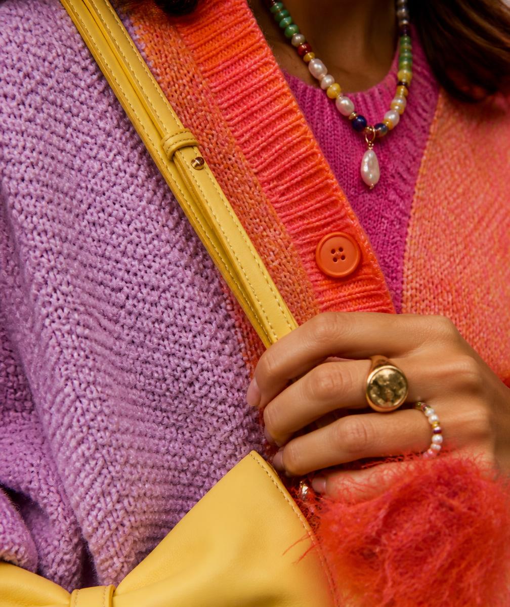 Close-up of layered colourful knitwear and gold jewellery