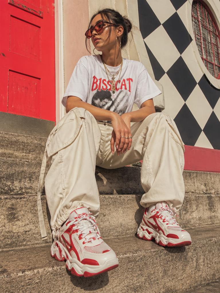 Woman seated on steps in wide leg cargo trousers and red and white statement chunky sneakers